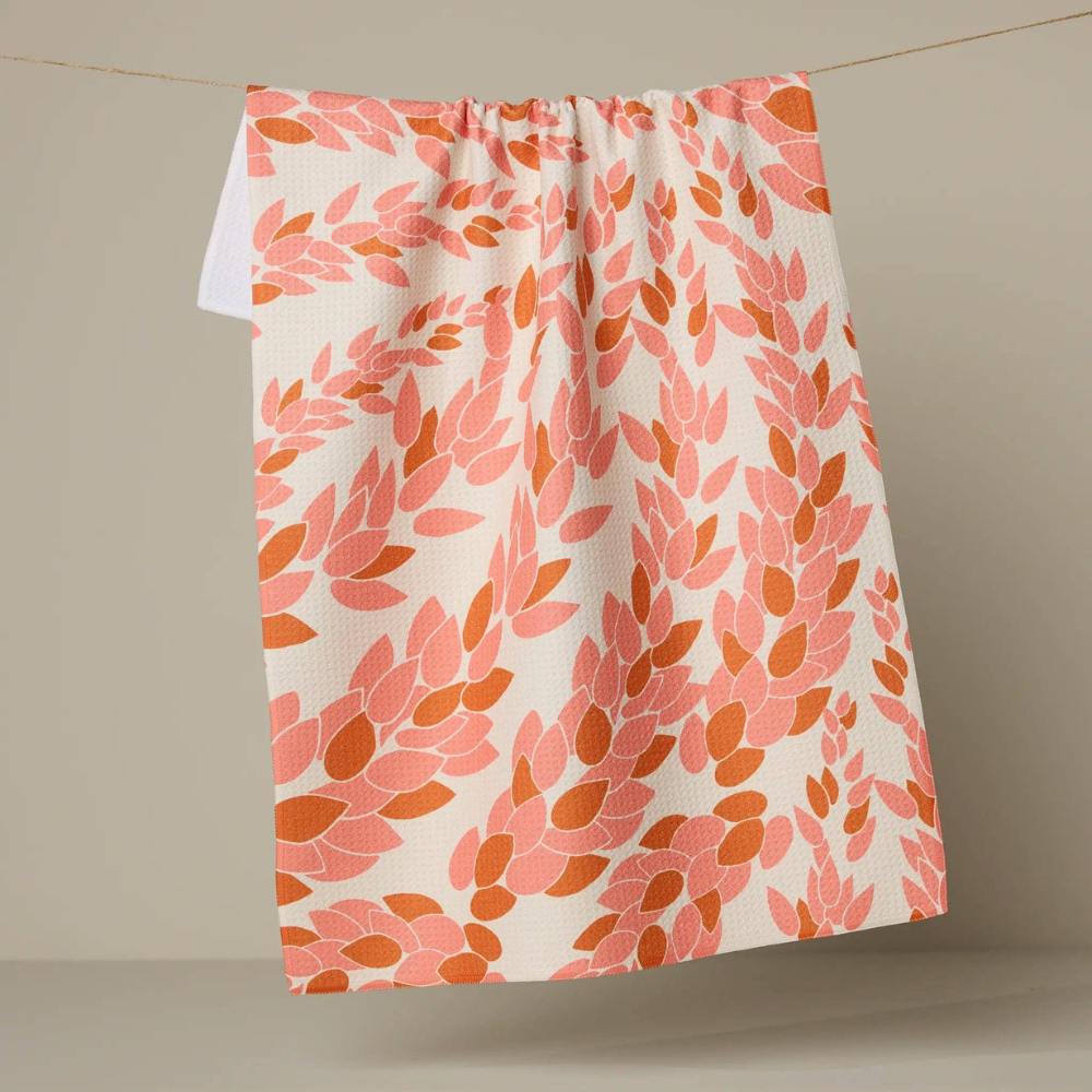 Coral and Orange floral patterned Geometry Tea towel hanging on a line against a beige background
