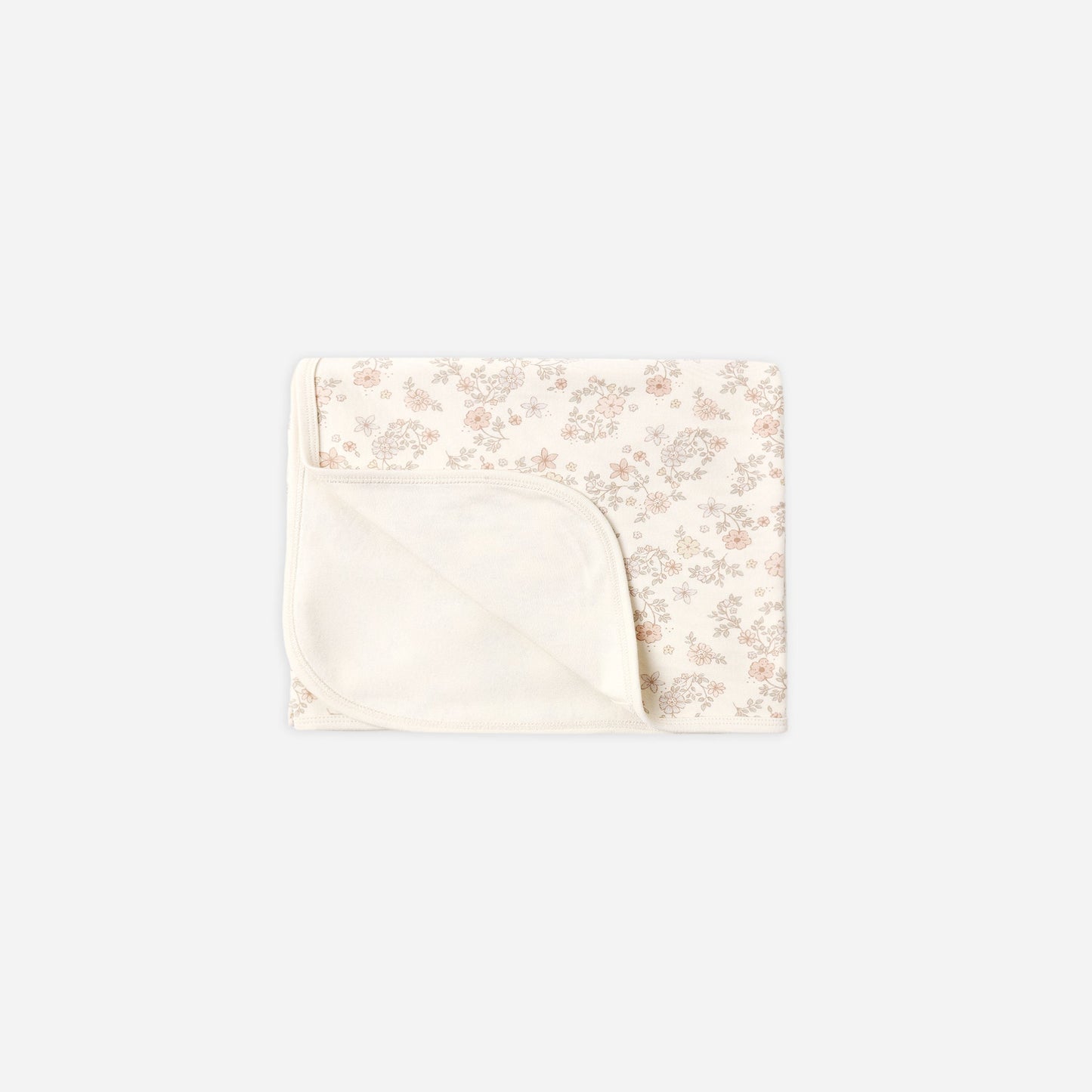 A folded baby blanket with a soft cream-colored solid fabric underside and a top half featuring a delicate, small-scale floral pattern in muted pink and beige on an off-white background.