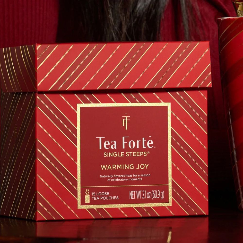 Close up of the Tea Forte Warming Joy Single Steeps box in a dark red setting