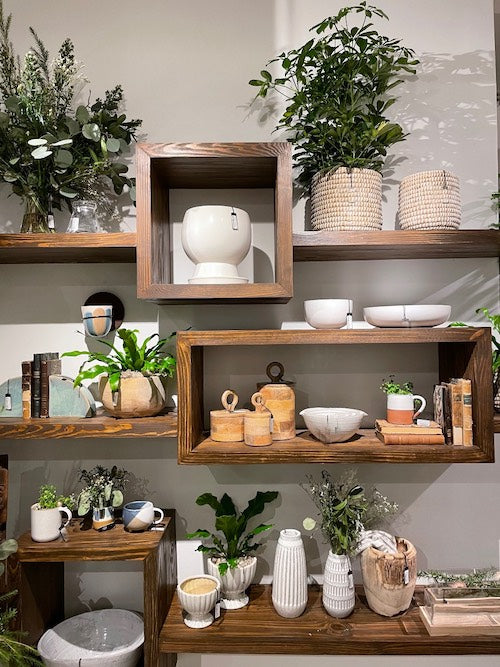 Home decor with natural color wood shelving, plants, white ceramic and wood accessories