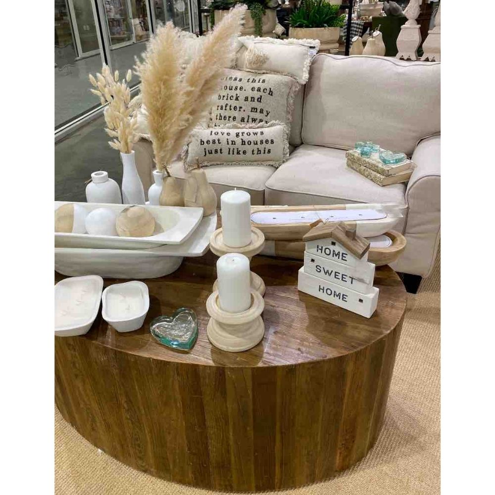 Home decor trends include natural and white accessories shown here on round wood coffee table next to white linen sofa
