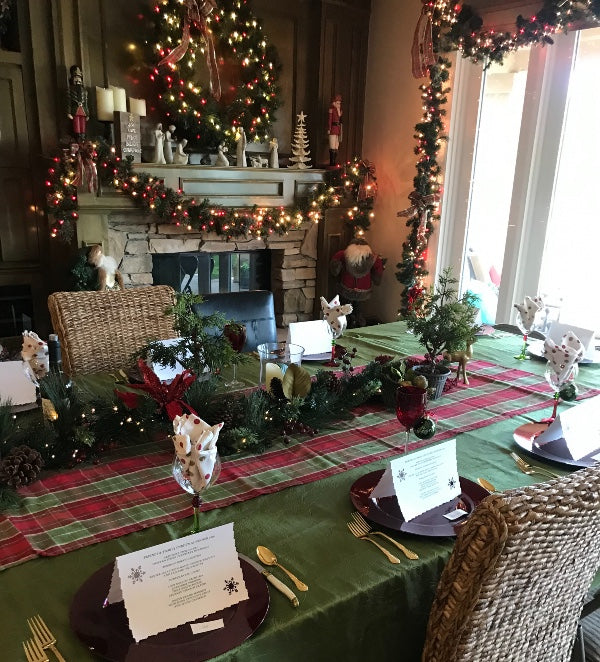 Holiday table set for Christmas dinner party inside of a festive home