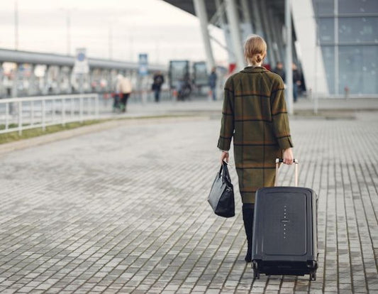 Woman walking away pulling suitcase into airport terminal