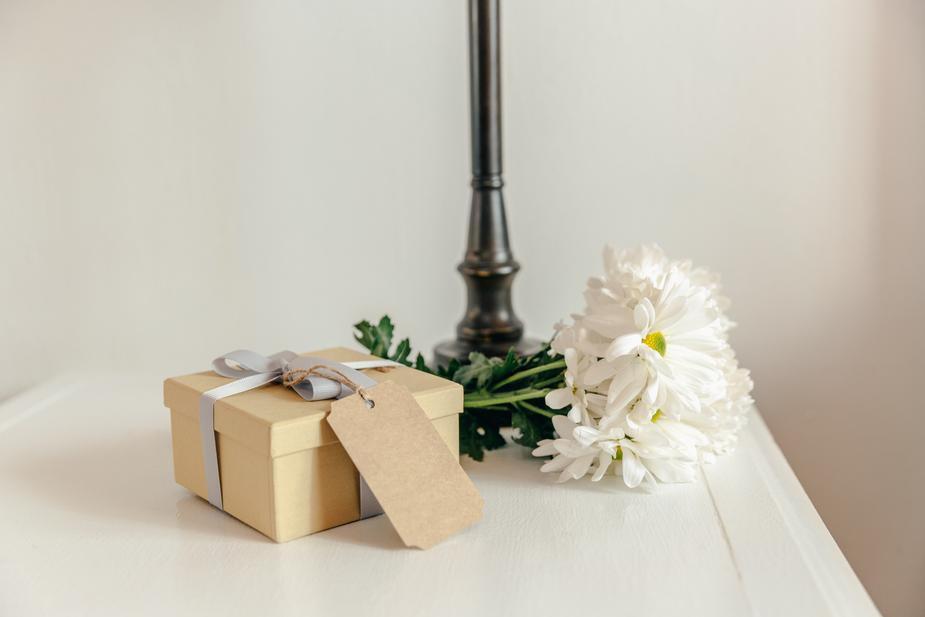 Gift on side table wrapped in natural paper with white flowers