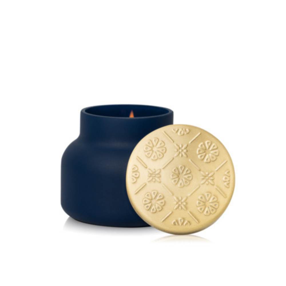 Lit Capri Blue Volcano Terrazza Velluto petite candle in matte navy with gold lid alongside