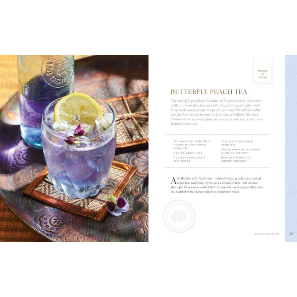 Butterfly Peach Tea with lemon wedge and edible flowers on a wooden coaster, next to a glass of blue liquid.