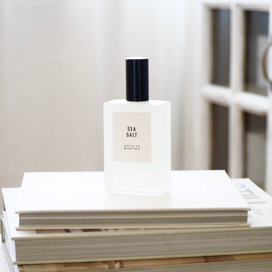 House of Mahina Sea Salt Room + Linen Mist, frosted glass bottle with black cap on a stack of white books
