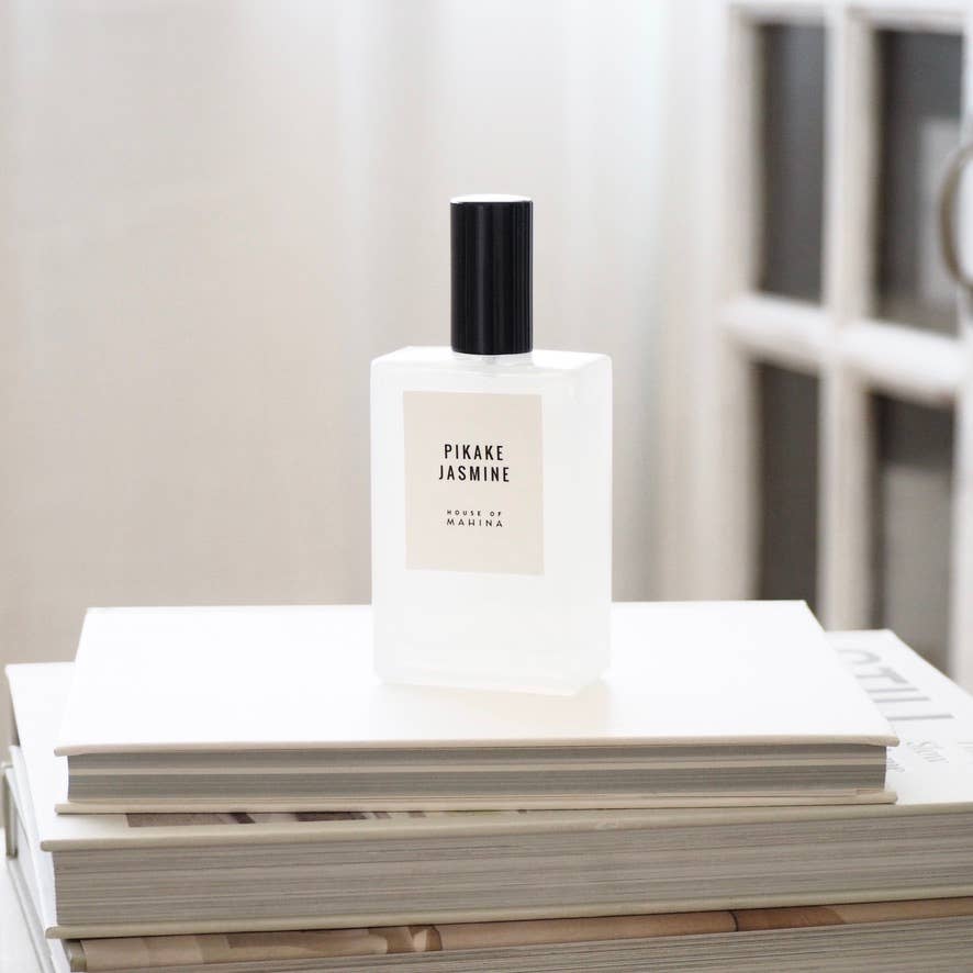 House of Mahina Pikake Jasmine Room + Linen Mist, frosted glass bottle with black cap on a stack of white books