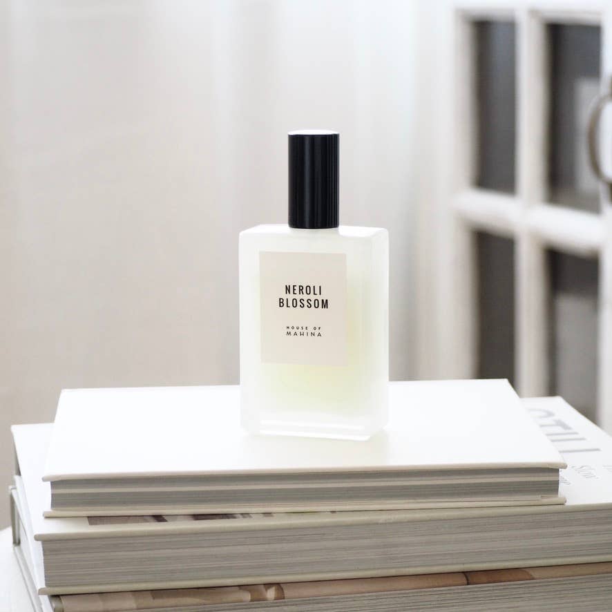 House of Mahina Neroli Blossom Room + Linen Mist, frosted glass bottle with black cap on a stack of white books