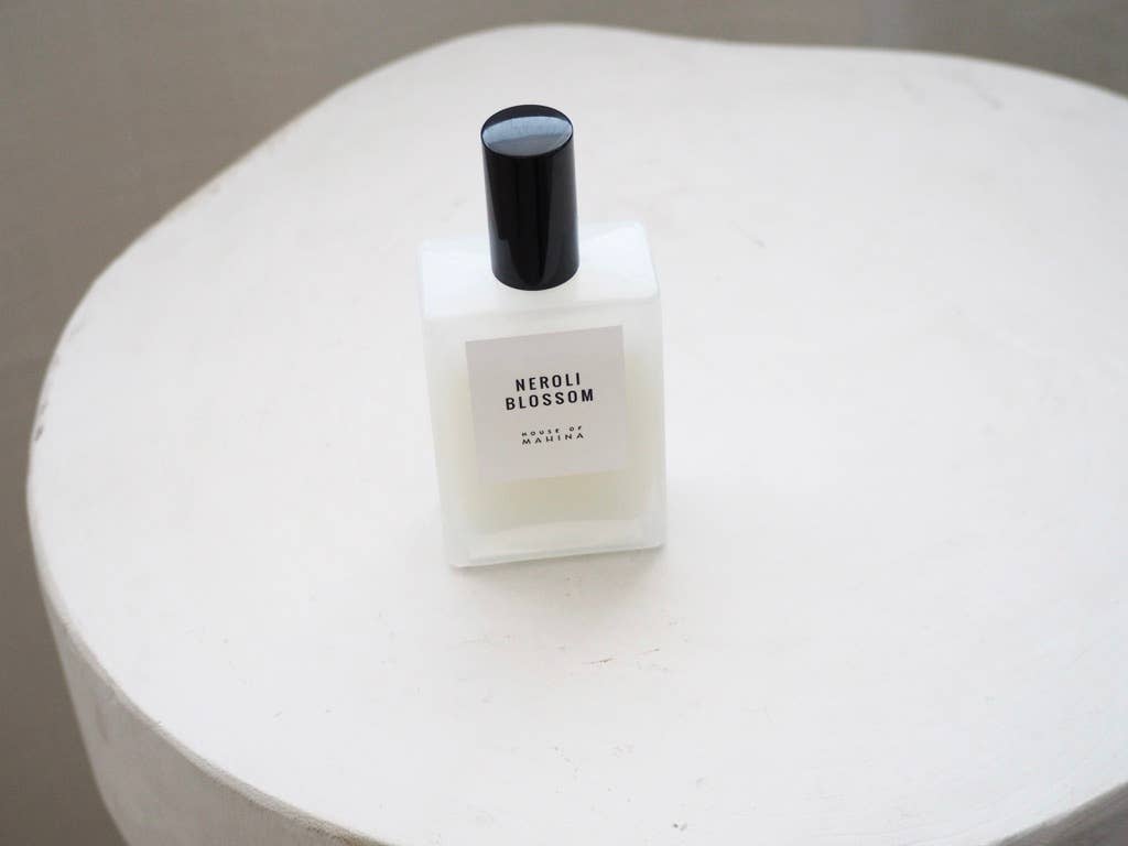 Neroli Blossom mist bottle with black cap standing on a white textured table