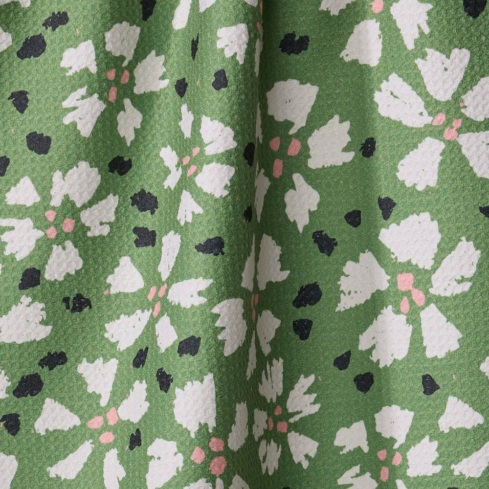 Close-up of Geometry Aster Tea Towel fabric with a floral pattern on a green background