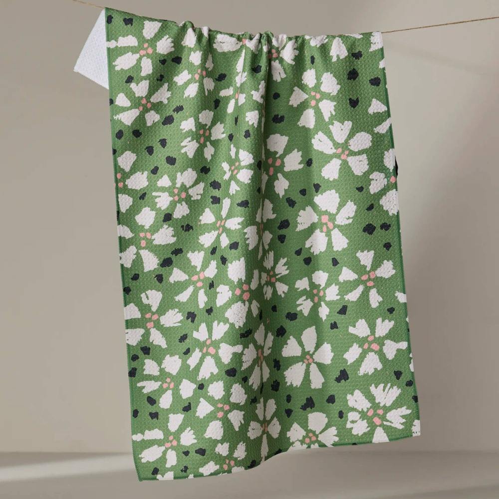 Green Geometry Tea Towel with white floral pattern hanging on a line against a neutral background