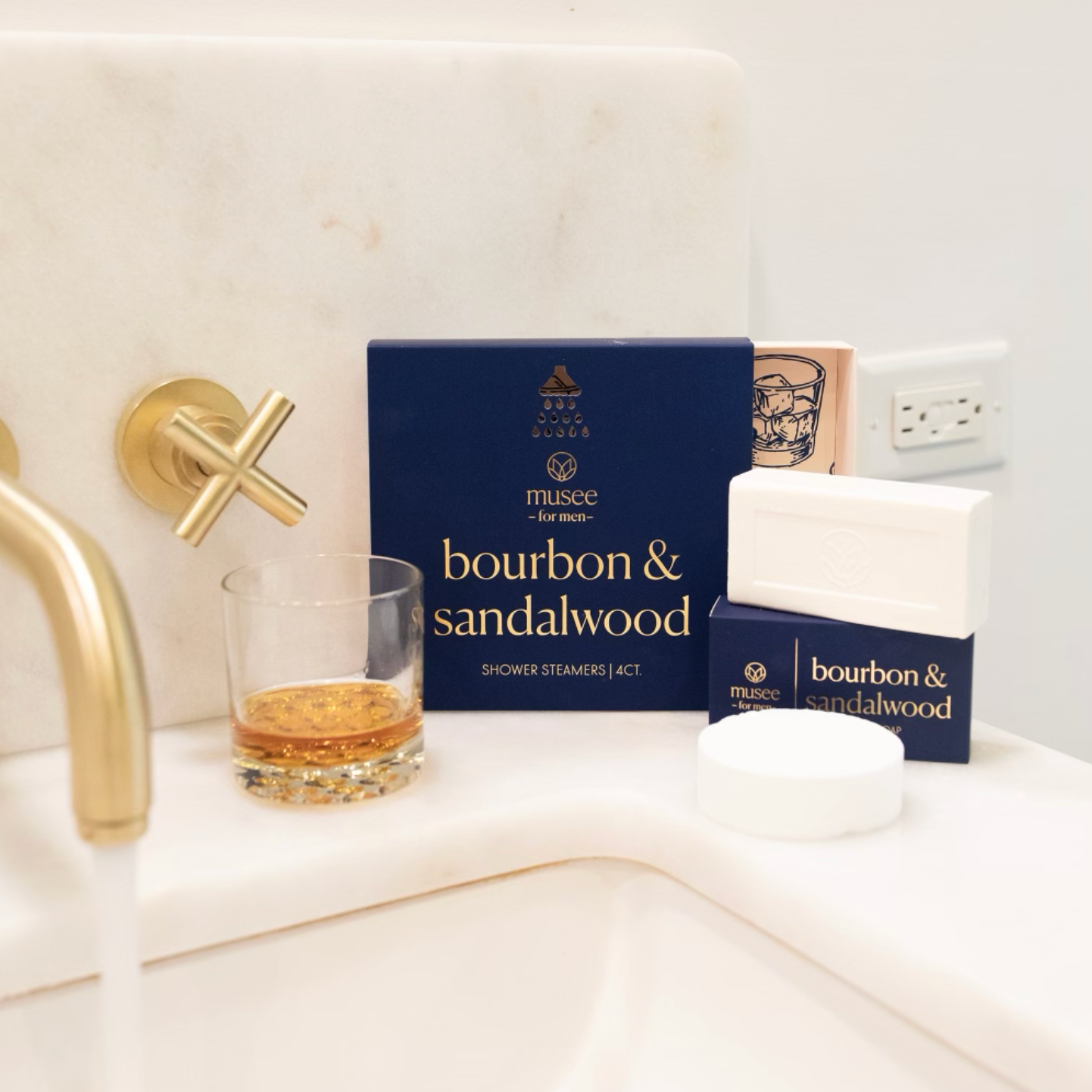 Off white bathroom sink with a glass of bourbon on sink counter alongside Bourbon and Sandalwood Bath Steamer box and Bar Soap