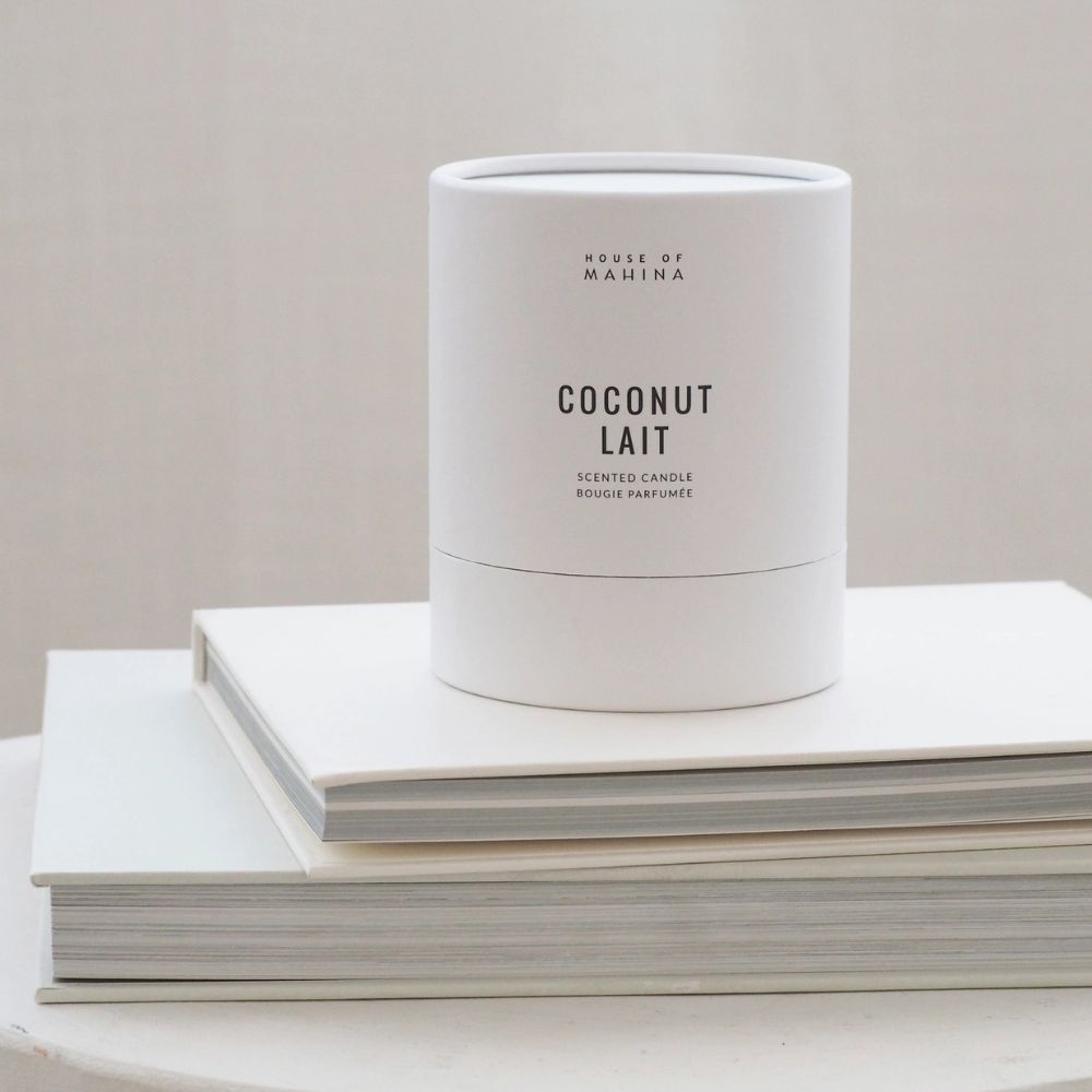 Coconut Lait Candle on stack of white books