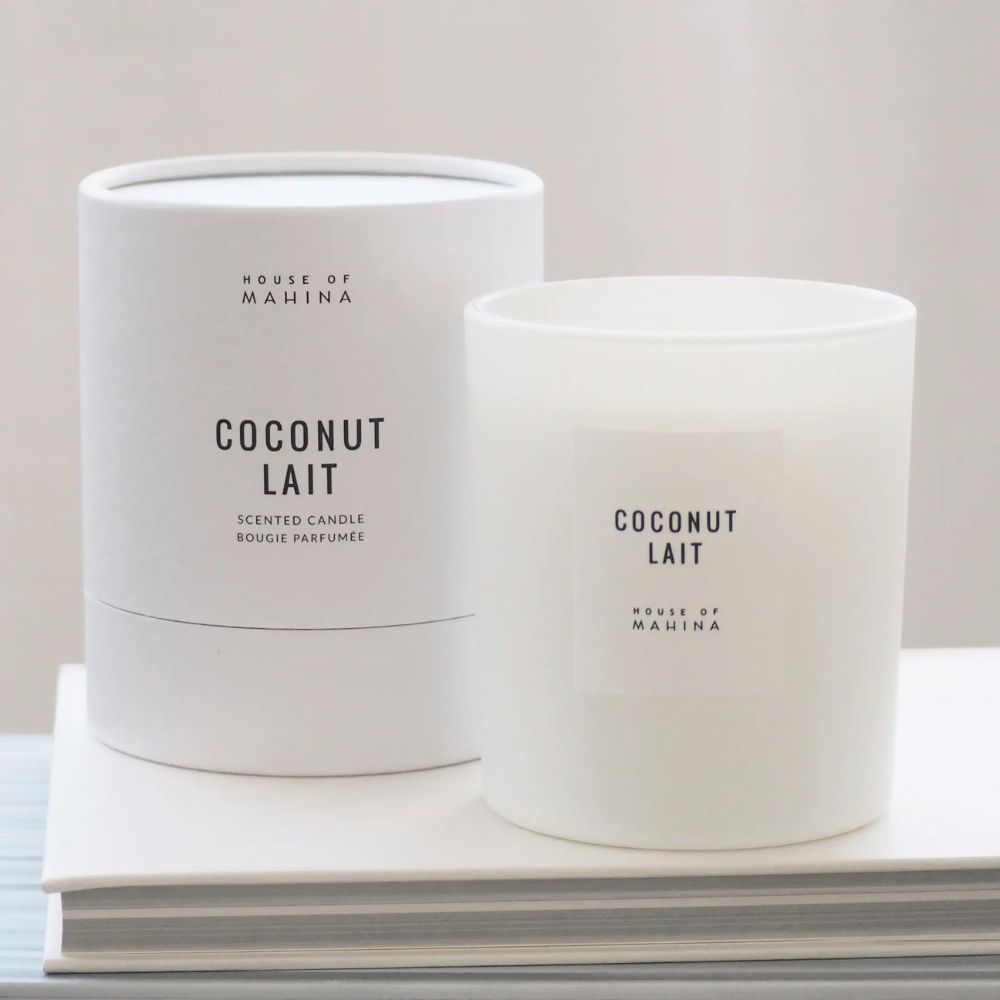 Coconut Lait Candle and round box on stack of white books 