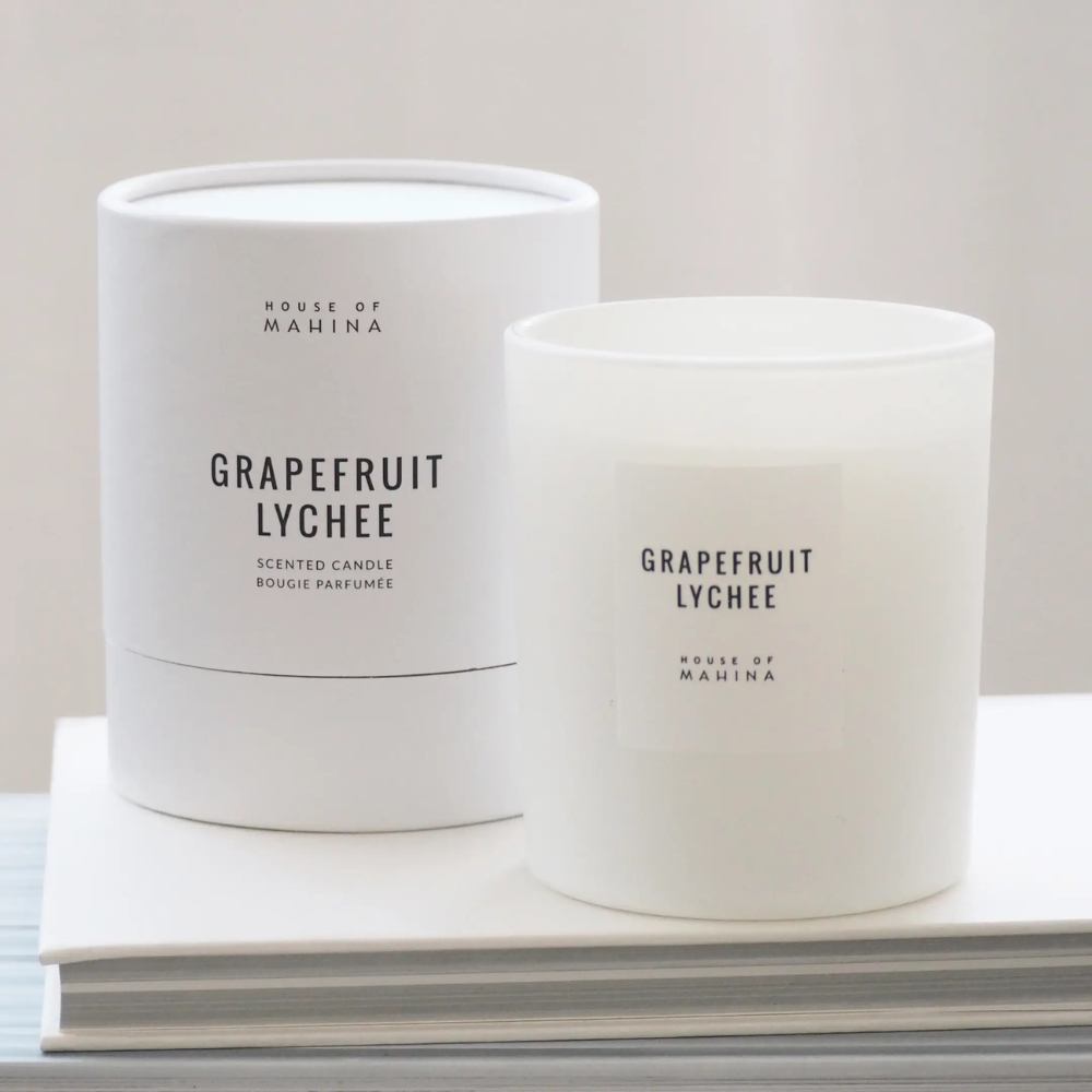 Grapefruit lychee candle with round candle box on stack of white books