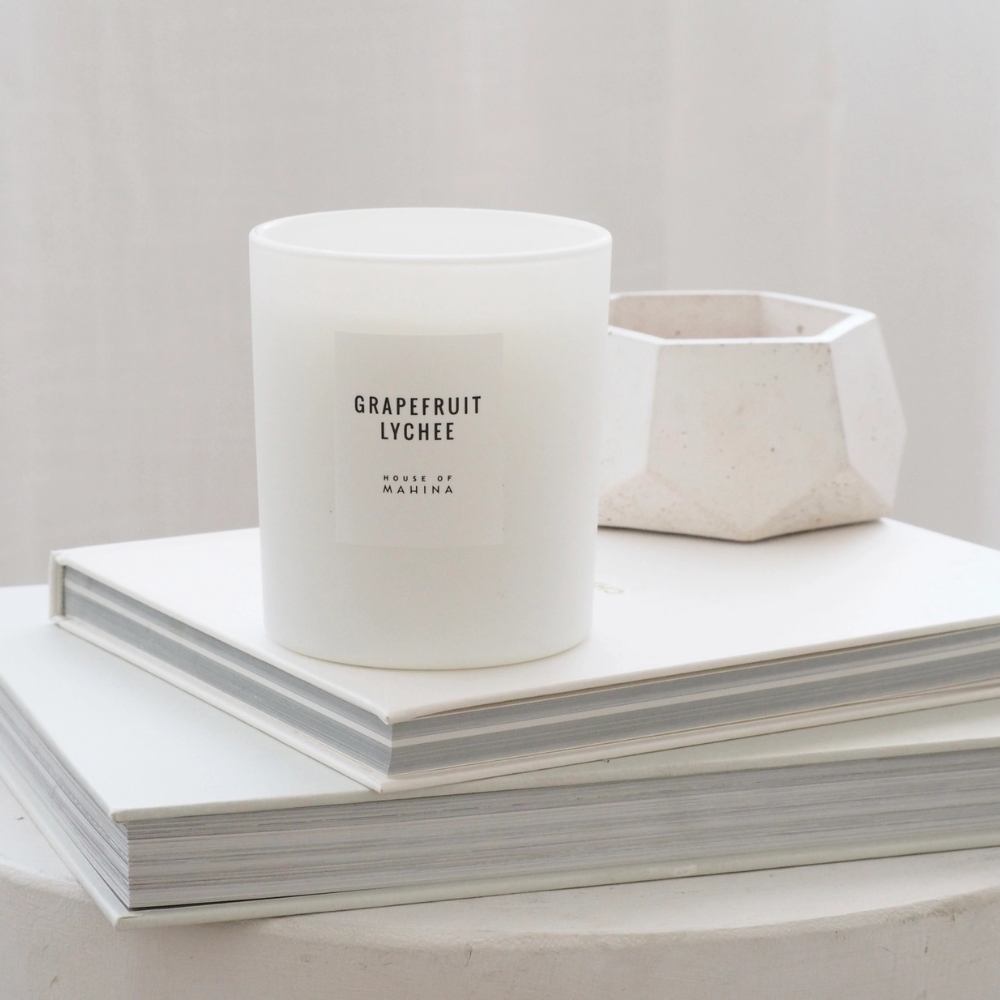 Grapefruit lychee candle with white round bowl on stack of books