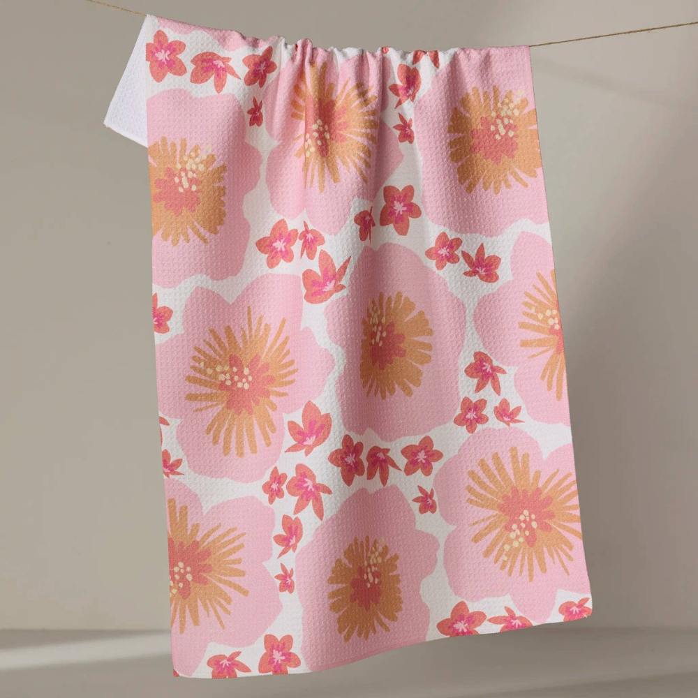 Pink and coral floral patterned Geometry Tea towel hanging on a line against a neutral background