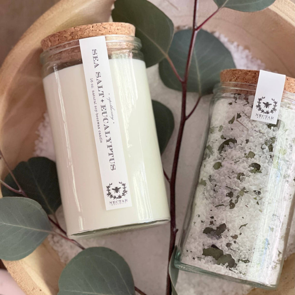 Nectar Republic Sea Salt and Eucalyptus bath salt jars on wooden surface with fresh eucalyptus