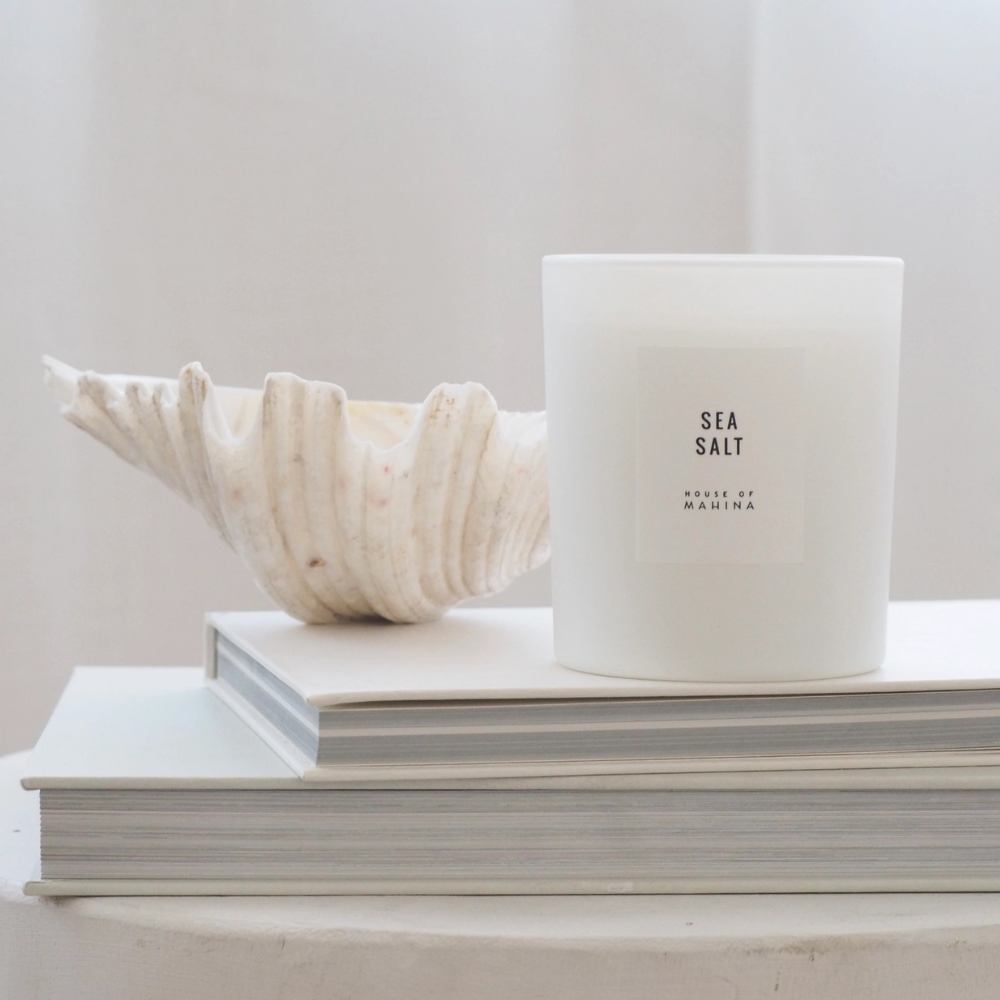 Sea Salt candle on stack of white books with shell on top 