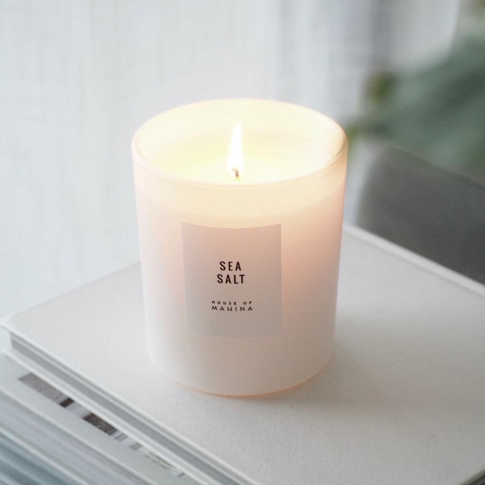 Lit Sea Salt candle on stack of white books in living room