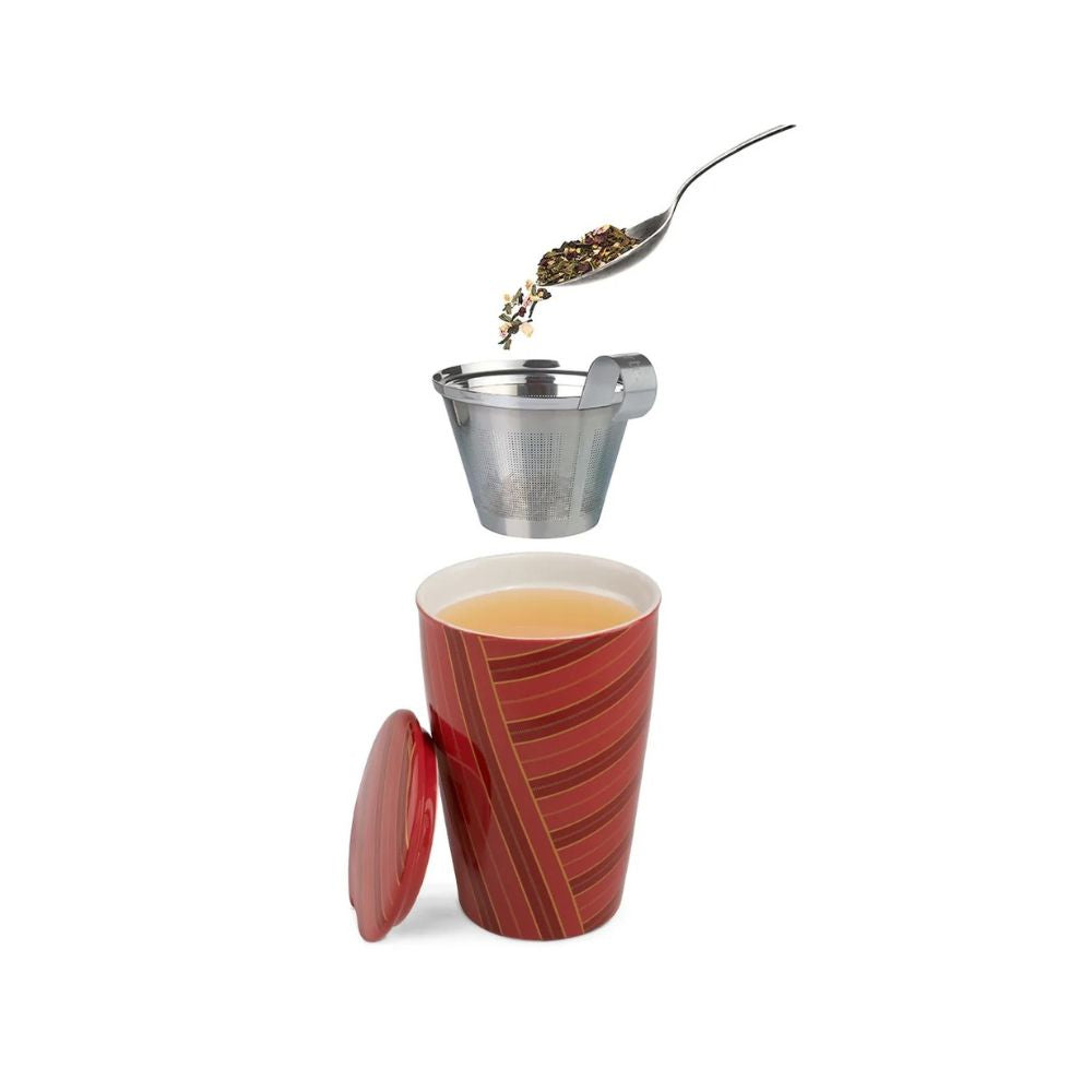 Warming Joy Kati cup with lid off, stainless steel infuser basket above and a spoon pouring loose tea