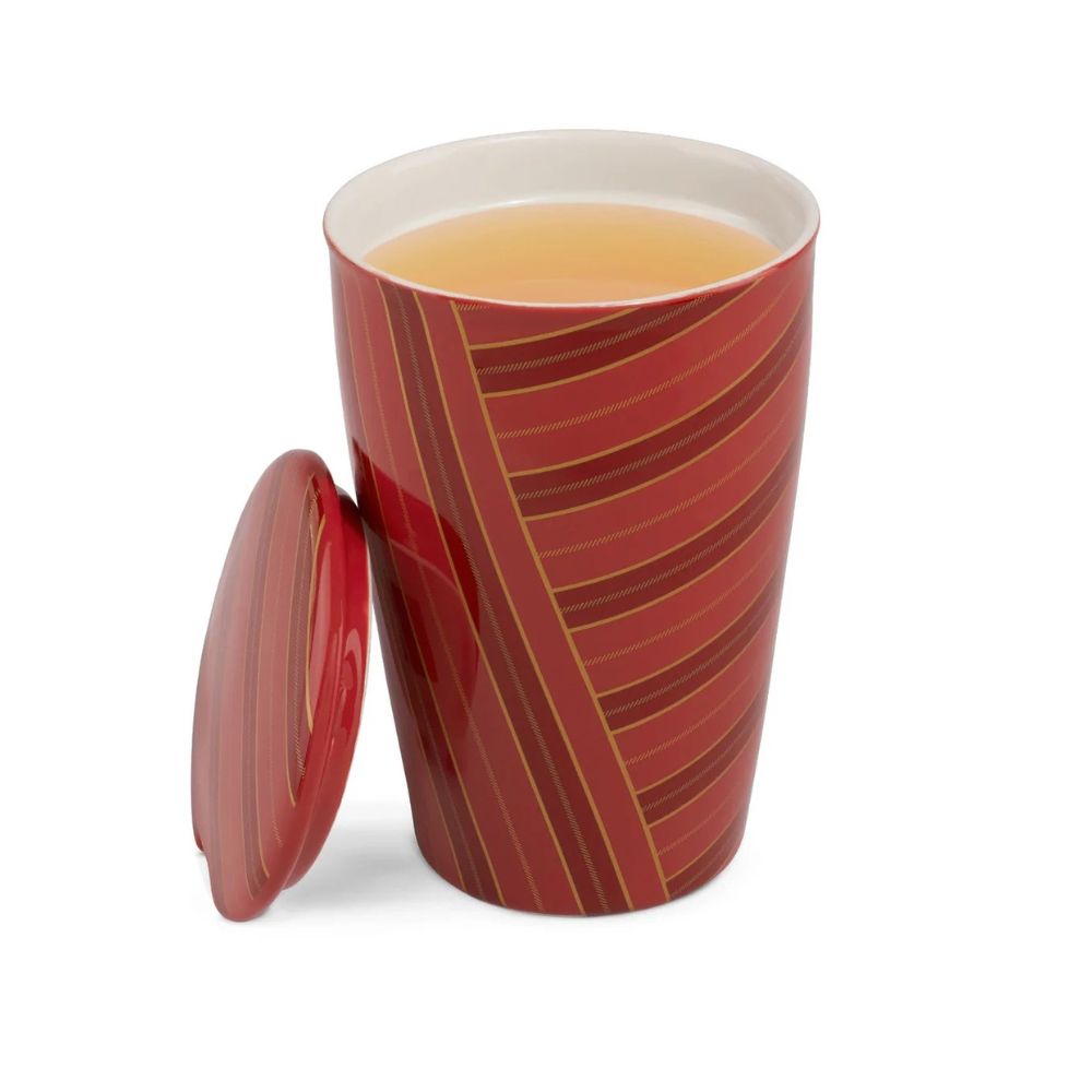 Red striped Tea Forte Warming Joy Kati cup filled with tea, lid leaning against the cup