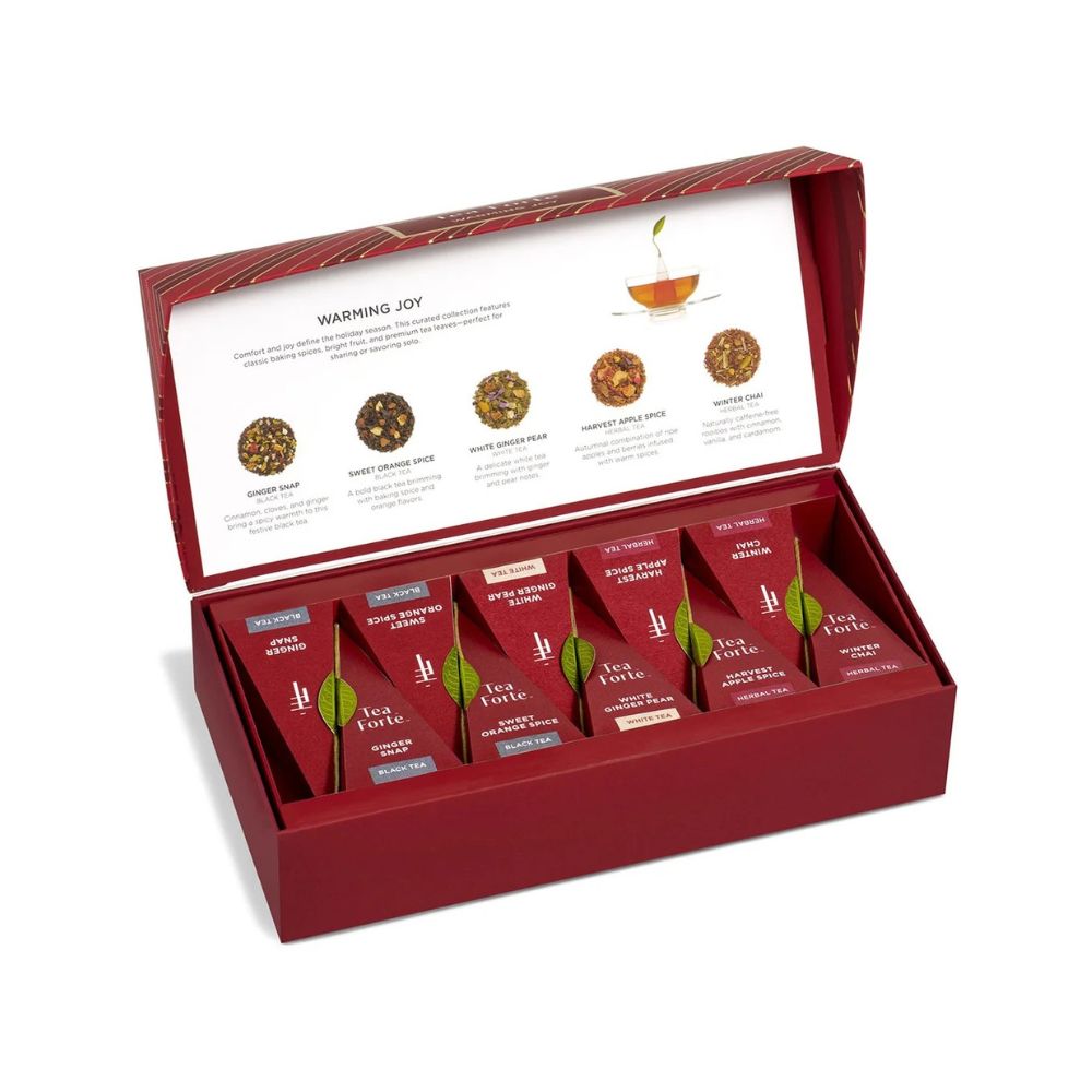 Close view of the open Warming Joy Petite Presentation Box with pyramid tea infusers beneath the tasting menu lid