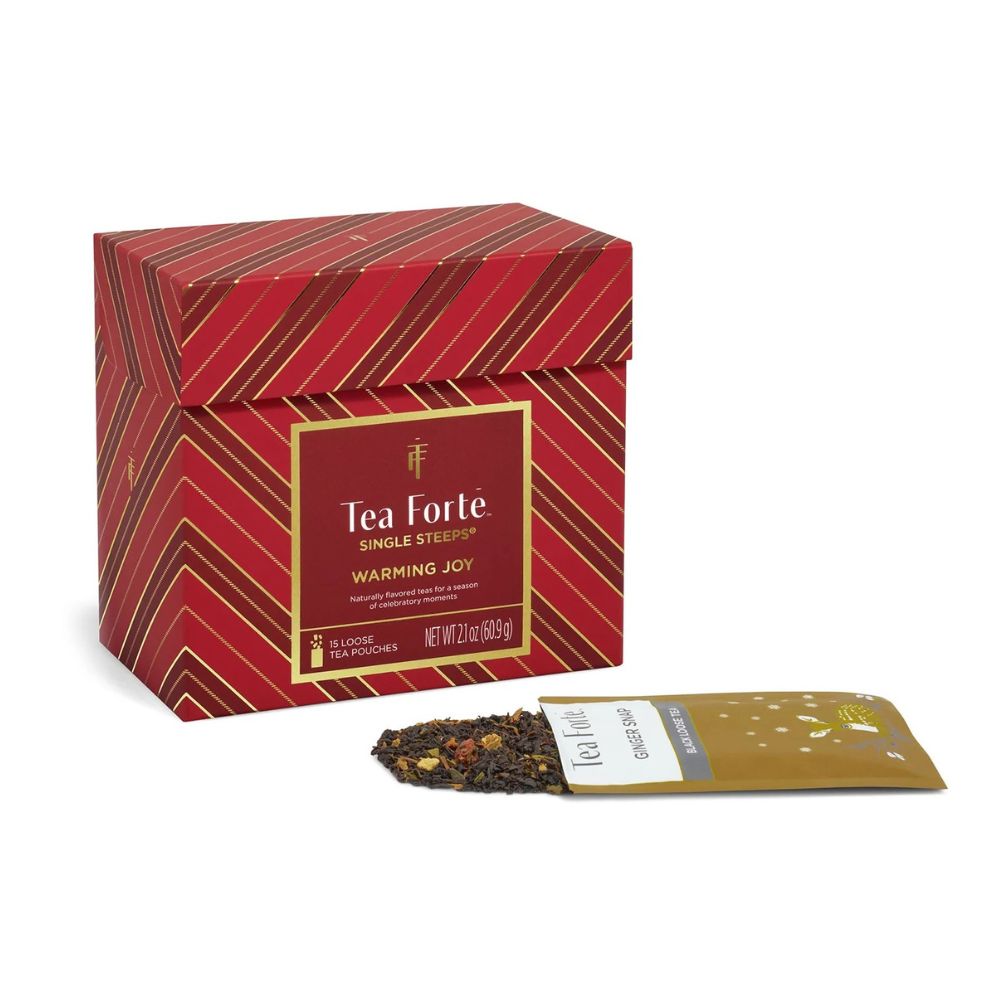 Warming Joy Single Steeps box with an open gold tea pouch and loose tea spilled in front