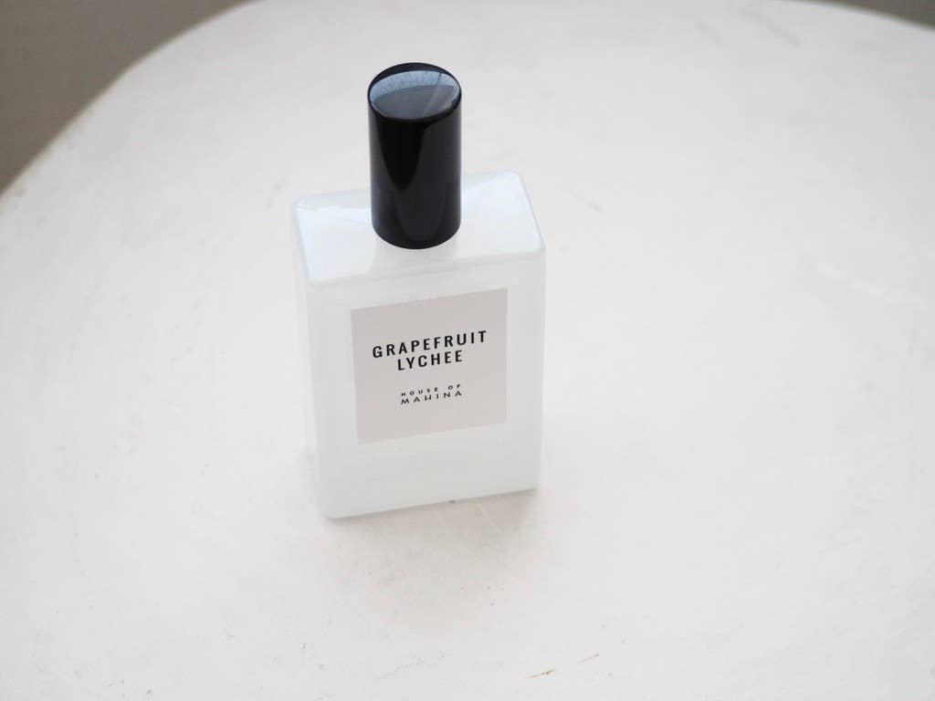 Grapefruit Lychee mist bottle with black cap standing on a white textured table